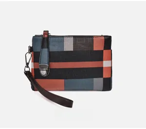Close-up of geometric patchwork clutch with wrist strap and cross-grain texture