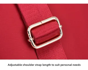 Detail of adjustable shoulder strap with gold metal buckle on red oxford fabric bag
