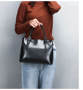 Close-up of black leather handbag featuring double handles and silver metal buckles