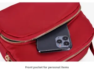 Front zipper pocket of red waterproof nylon crossbody bag holding a smartphone
