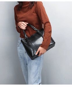 Large black patent leather tote bag with silver metal rings and protective feet detail