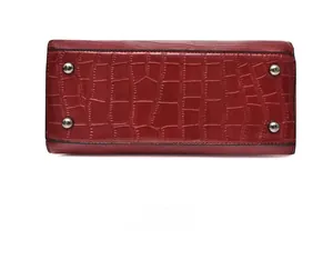 Détail de la base du sac rouge gaufré croco avec quatre pieds de protection en métal argenté