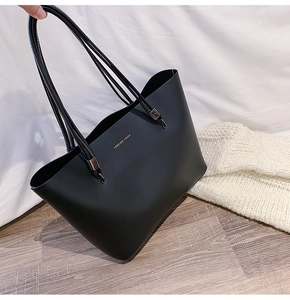 Detail of black tote bag featuring Forever Young gold lettering and long shoulder strap