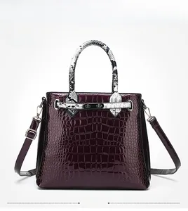 Detail of purple croc-embossed handbag with snakeskin pattern handle and metallic buckle