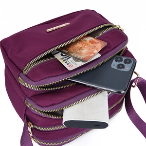 Waterproof purple nylon crossbody bag with multiple zipper compartments for storage