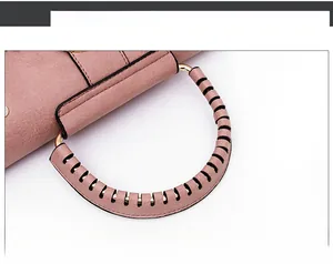 Detail of pink leather handbag featuring a round gold metal handle with wrapped strap texture