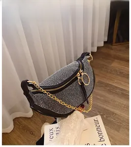 Detailed close-up of a black crescent rhinestone bag with gold chain strap held by hand