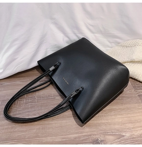 Detail of black faux leather tote bag with Forever Young gold logo and slim shoulder strap