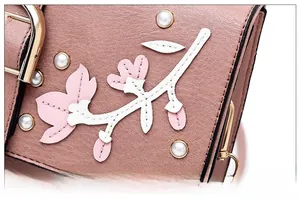 Detail of dry rose leather handbag featuring 3D floral appliques and pearl accents