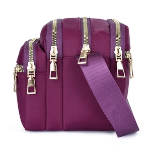 Waterproof purple nylon crossbody bag with multiple gold zippers and adjustable strap