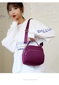 Detail of purple waterproof nylon crossbody bag featuring multi-layer zipper compartments