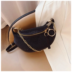 Close-up of black rhinestone moon bag with gold chain on a luxury beige leather seat
