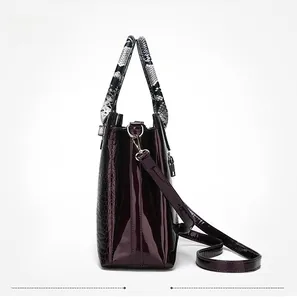 Macro detail of wine red patent leather handbag with crocodile pattern and snake print handle