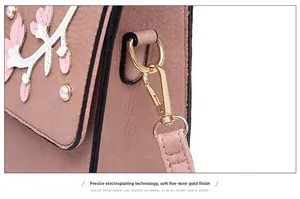 Detailed macro view of gold-plated hook and floral embroidery on pink leather bag