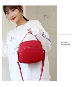 Detail of red waterproof nylon crossbody bag with three golden zip compartments