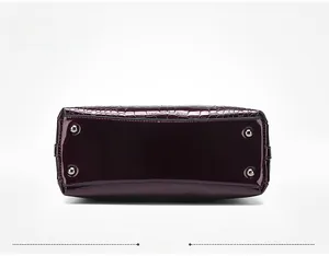 Detail view of purple crocodile embossed handbag base with silver anti-wear metal studs