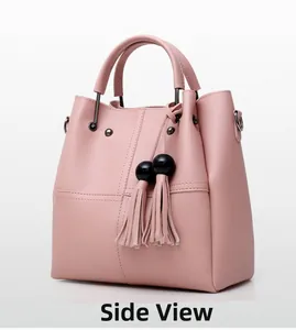 Detail view of pink PU leather tote with tassel charms and metallic hardware accents
