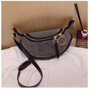Close-up of sparkling silver rhinestones on black crescent bag with gold hardware