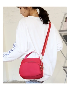 Red waterproof nylon mini crossbody bag shown worn by a model in a casual setting