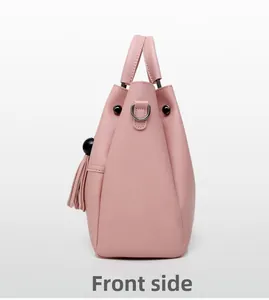 Side view of pale pink bucket bag featuring metal hardware and tassel charm detail