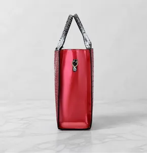 Detail view of red crocodile pattern tote with snakeskin handle and gold metal ring