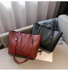 Close-up of burgundy and black tote bags with Forever Young print on a sofa