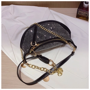 Close-up of black rhinestone saddle bag with gold metal chain and leather strap details