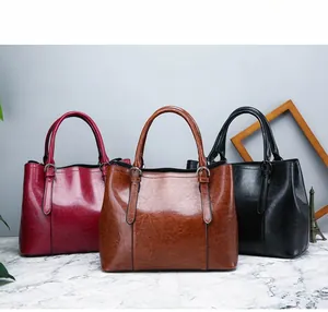 Detailed view of large glossy leather handbags in burgundy, brown, and black colors