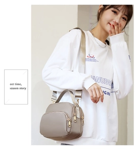 Detail of taupe oxford cloth crossbody bag with multiple zip pockets and wide strap