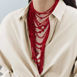 Detail of bohemian layered red coral bead multi-strand long bib necklace on model