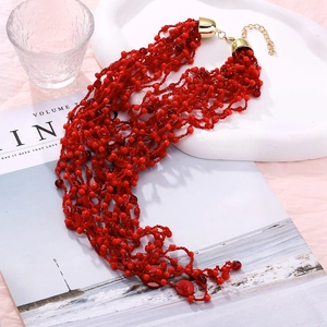 Detail of coral red multi-layer beaded necklace with gold lobster clasp and extension chain