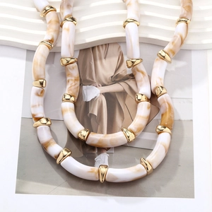 Detail of chunky resin beads with cloud texture and gold accents on layered necklace