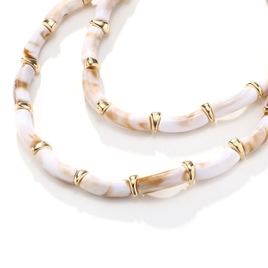 Detailed macro view of resin beaded necklace with marble texture and golden metal spacers