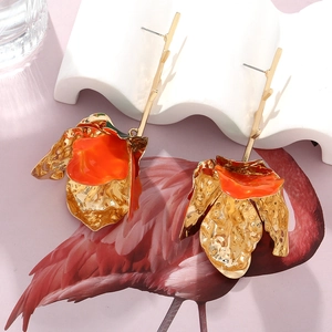 Detailed close-up of multilayer orange enamel flower earrings with golden metallic finish