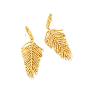 Detail of long gold leaf earrings with hammered metal texture and bohemian feather design