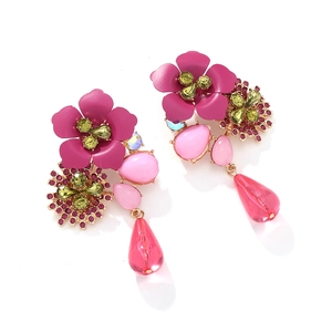 Detailed shot of bohemian multi-layered floral earrings with pink petals and green crystals