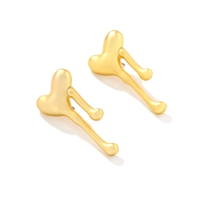 Macro detail of abstract lava-style matte gold heart earrings with molten metal texture