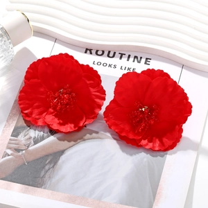 Boucles d'oreilles bohèmes fleurs en tissu rouge avec cœur en cristal sur fond de magazine