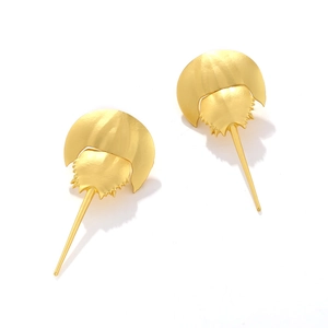 Detailed close-up of matte gold horseshoe crab earrings with intricate marine textures