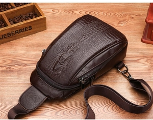 Crocodile pattern leather chest bag for men on a wooden desk with vintage decor