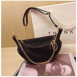 Close-up of black rhinestone moon bag with gold chain on a wooden lifestyle background