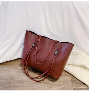 Detail of burgundy leather tote bag with Forever Young text on a white bed