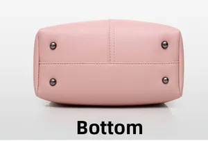 Detail view of pink leather bag bottom with four protective metal studs and stitching