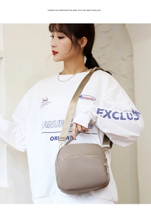 Detail of beige nylon crossbody bag featuring waterproof fabric and gold zipper