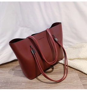 Detail of burgundy tote bag with Forever Young text on textured leather and metal rings