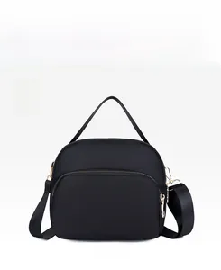 Close-up of black waterproof nylon crossbody bag with gold zippers and detachable wide strap