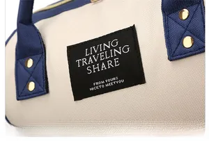 Close-up of canvas backpack showing blue straps with gold rivets and travel logo tag