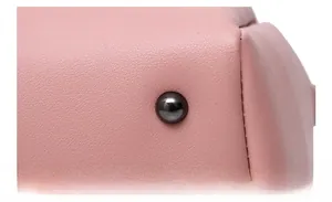 Detailed macro view of pink litchi leather bag bottom corner with metal studs