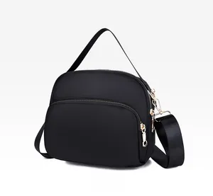 Macro side view of black waterproof nylon crossbody bag with dual golden zippers