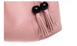 Detail of pink faux leather bag with black round pompom and fringe tassel charm